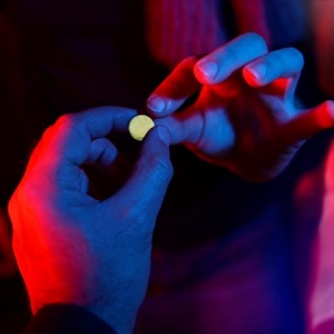 image of a teen handing a pill to another teen