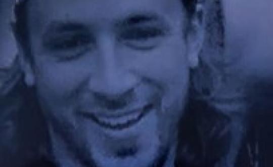 Adam moser wearing a bandana, smiling at the camera