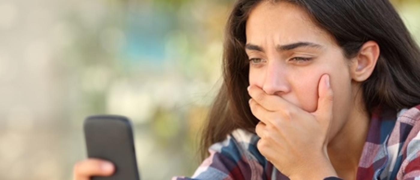worried teen looking at a cell phone